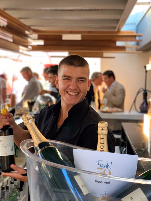 Krama team member welcoming private-event guests with chilled champagne