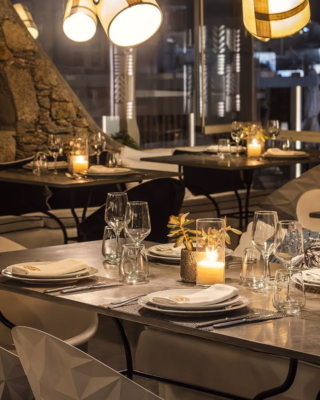 Candlelit dining tables with a panoramic Mykonos night view